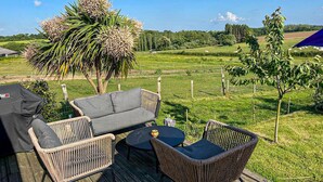 An outdoor deck with wicker furniture, a grill, and a view of a green landscape. - 4 bedroom awesome home in Taulé (Taulé)