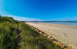 Une plage bordée d’une côte rocheuse et de dunes herbeuses.