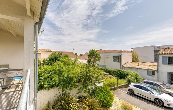 A residential area with houses, a balcony, and parked cars. - Appartement Proche Plage (La Rochelle)