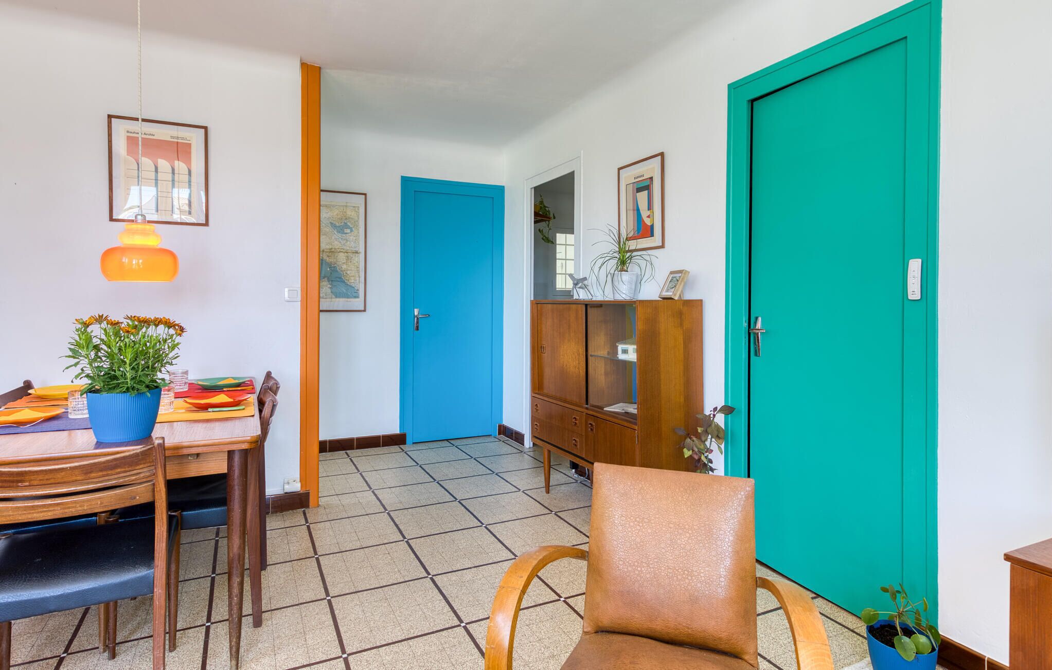 Un coin repas avec une table en bois, des chaises, une plante en pot et un meuble bleu.