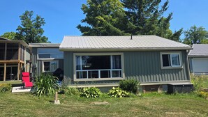 A single-story house with a front porch, a covered patio, and a lawn. - Charming 3-bedroom cottage in serene Trent Hills with WiFi (Trent Hills)