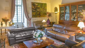 A living room with leather sofas, a coffee table with a vase of flowers, a cabinet with glass doors, and a painting on the wall. - Gorgeous home in Guérigny (Guérigny)