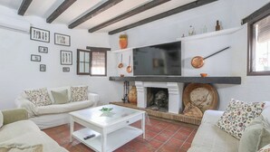 Ein Wohnzimmer mit Kamin, weißen Sofas, einem Fernseher und gerahmten Bildern an der Wand.