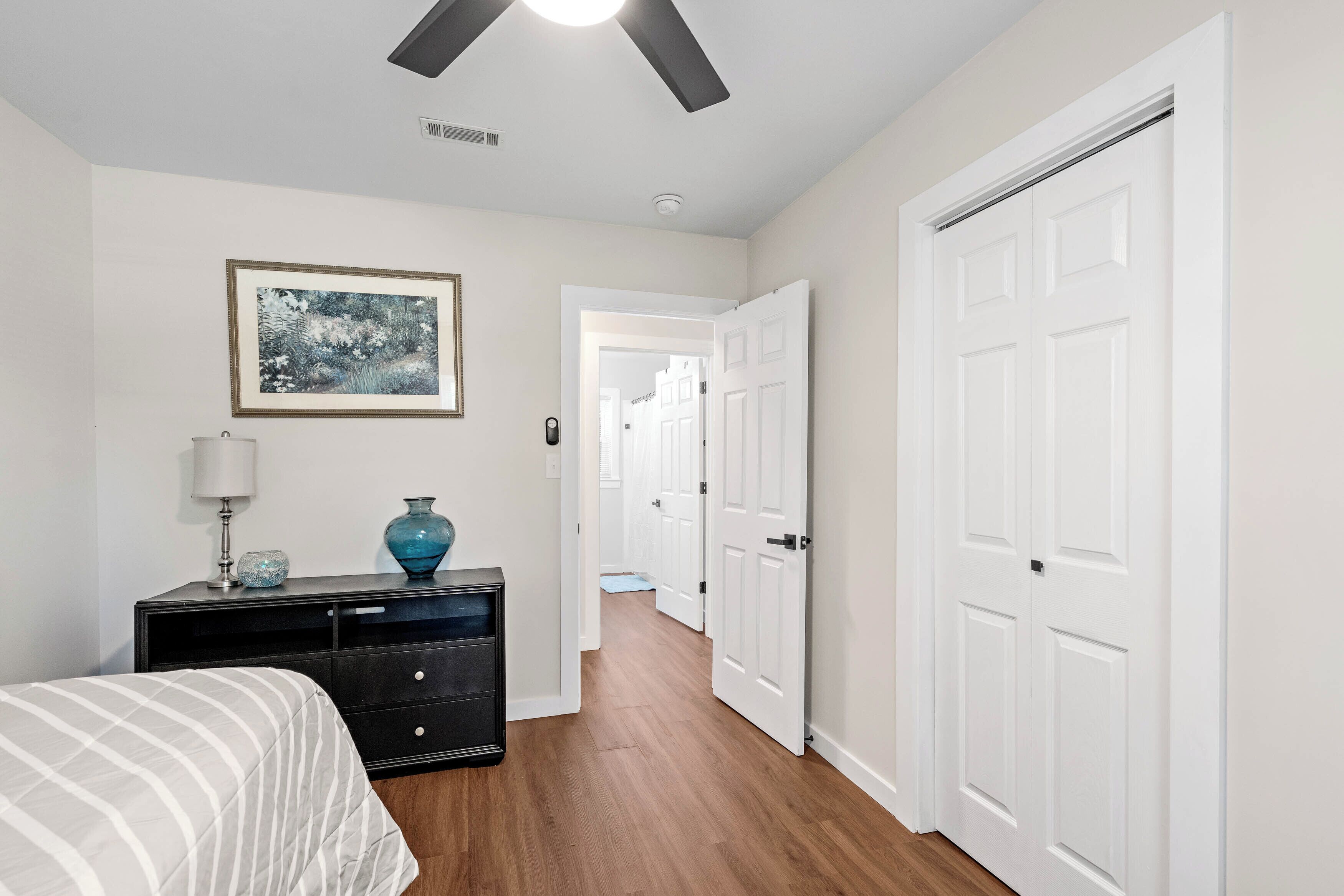 A bedroom with a bed, a dresser, a lamp, and a framed picture on the wall.