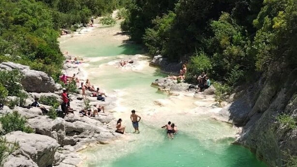 Une zone de sources chaudes naturelles, avec de l’eau claire, entourée de rochers et de verdure.