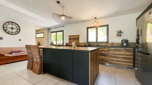 Une cuisine moderne dotée d’un îlot central, de meubles en bois et d’un grand réfrigérateur.