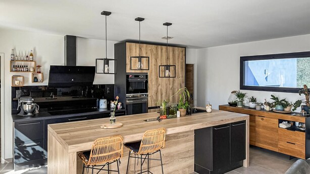 A modern kitchen with a central island, black appliances, wooden cabinets, and a large window. - Lovely home in Saint-Césaire-de-Gauzi with WiFi (Saint-Césaire-de-Gauzi)