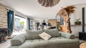 A modern living room with a grey sofa, a dining area, and a kitchen in the background. - Lovely home in Saint-Césaire-de-Gauzi with WiFi (Saint-Césaire-de-Gauzi)