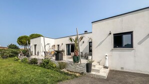 A modern building with a flat roof, large windows, and a paved patio area with outdoor furniture. - Lovely home in Saint-Césaire-de-Gauzi with WiFi (Saint-Césaire-de-Gauzi)