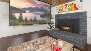 A living room with a fireplace, a large painting of a lake, and a wooden ceiling. - 3BR w/ shared Hot Tub & Backyard Oasis (Reno)