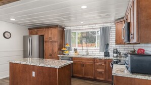 A modern kitchen with wooden cabinets, granite countertops, and stainless steel appliances. - 3BR w/ shared Hot Tub & Backyard Oasis (Reno)