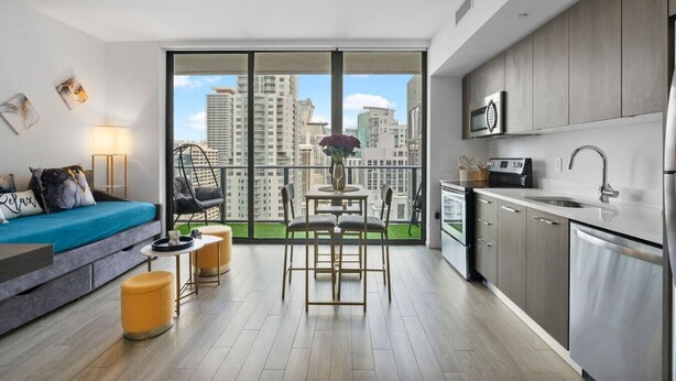 A modern apartment with a balcony, a kitchen, and a living area with a sofa and chairs. - New Penthouse Downtown Heated pool & jacuzzi (Miami)