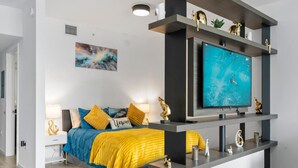 A modern bedroom with a bed, a TV mounted on a wall, and a painting above the bed. - New Penthouse Downtown Heated pool & jacuzzi (Miami)