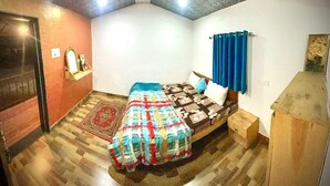 Une chambre à coucher avec un lit, un ventilateur de plafond, une armoire en bois et un tapis à motifs.