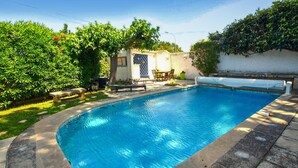 A rectangular swimming pool with a tiled deck surrounding it. There is a small patio area with a table and chairs, and a bench. - Beautiful home in Morières-lès-Avignon (Morières-lès-Avignon)