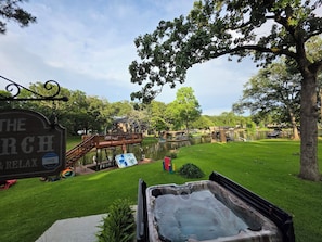 A hot tub in a grassy area with a wooden deck and a sign that reads "The Church Relax".