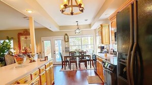 A spacious kitchen with wooden flooring, a large island, and a black refrigerator. - Lakefront, Boat dock, Fishing, Fire pit, Kayak, pedal boat, Paddle board (Mabank)