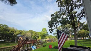 A park with a wooden bridge, a pond, and an American flag. - Lakefront, Boat dock, Fishing, Fire pit, Kayak, pedal boat, Paddle board (Mabank)