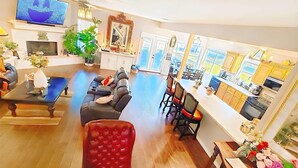 A spacious living room with a large TV, comfortable seating, a dining area, and a kitchen with large windows. - Lakefront, Boat dock, Fishing, Fire pit, Kayak, pedal boat, Paddle board (Mabank)