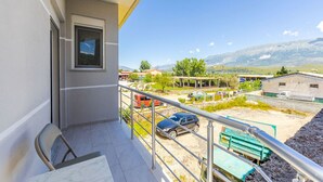 Un balcon donnant sur un parking, des immeubles et des montagnes.