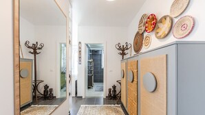A hallway with a mirror, a patterned rug, and decorative wall hangings. - Talea Joyful Stay by PikHost by PikHost (Tale)