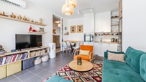 A modern living room with a flat-screen TV, bookshelves, a coffee table, and a sofa. - Talea Joyful Stay by PikHost by PikHost (Tale)