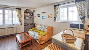 A cozy living room with a sofa, a coffee table, a bookshelf, and a microwave. - 1 bedroom gorgeous home in La Tranche-sur-Mer (La Tranche-sur-Mer)