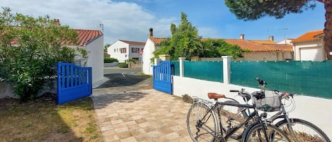 En asfalteret sti, der fører til en portindgang, med en cykel parkeret i nærheden.