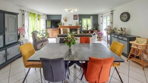 A dining area with a large table, chairs, and a vase of flowers.