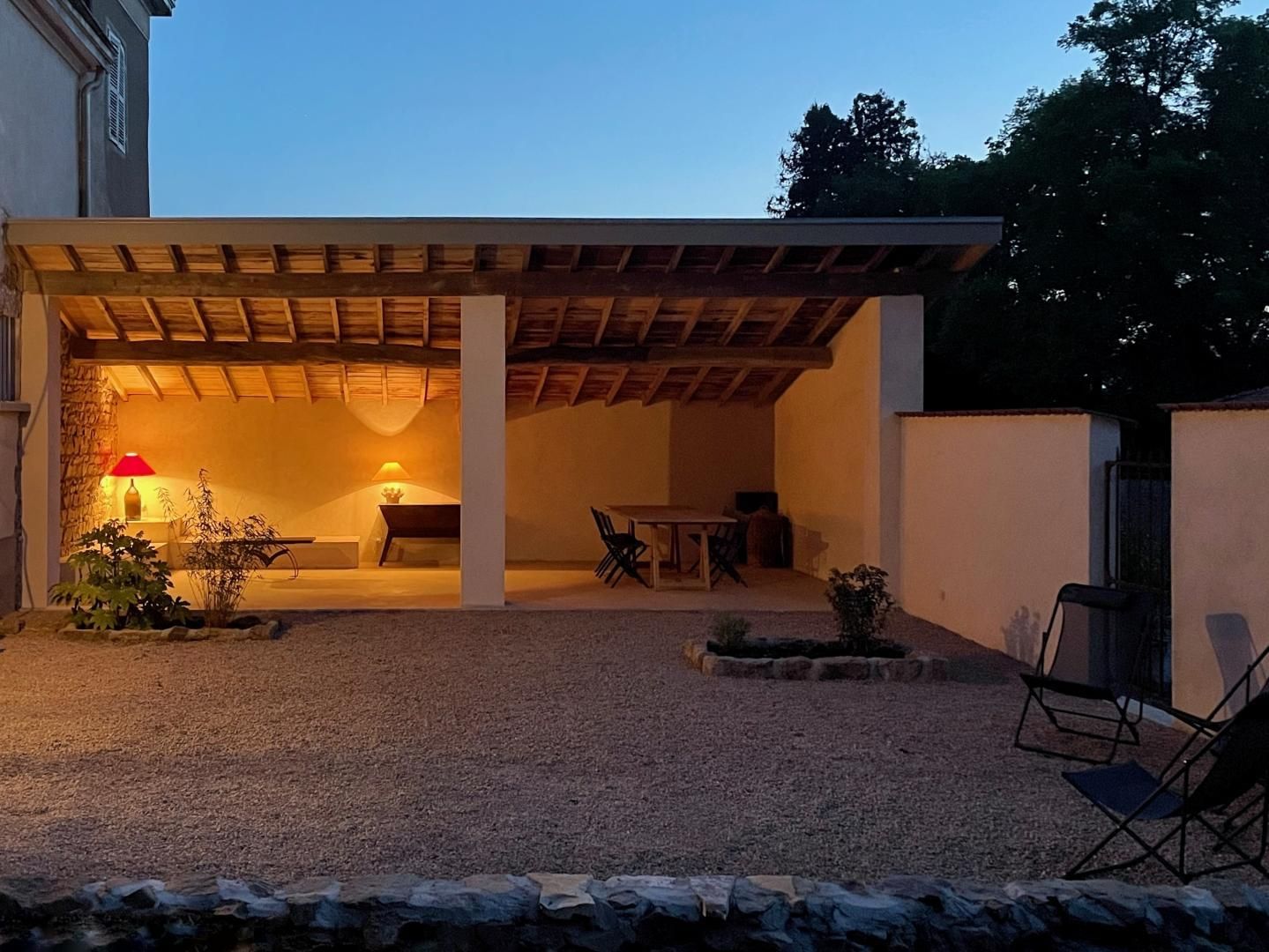 An outdoor patio area with a covered seating space, a table, and chairs.