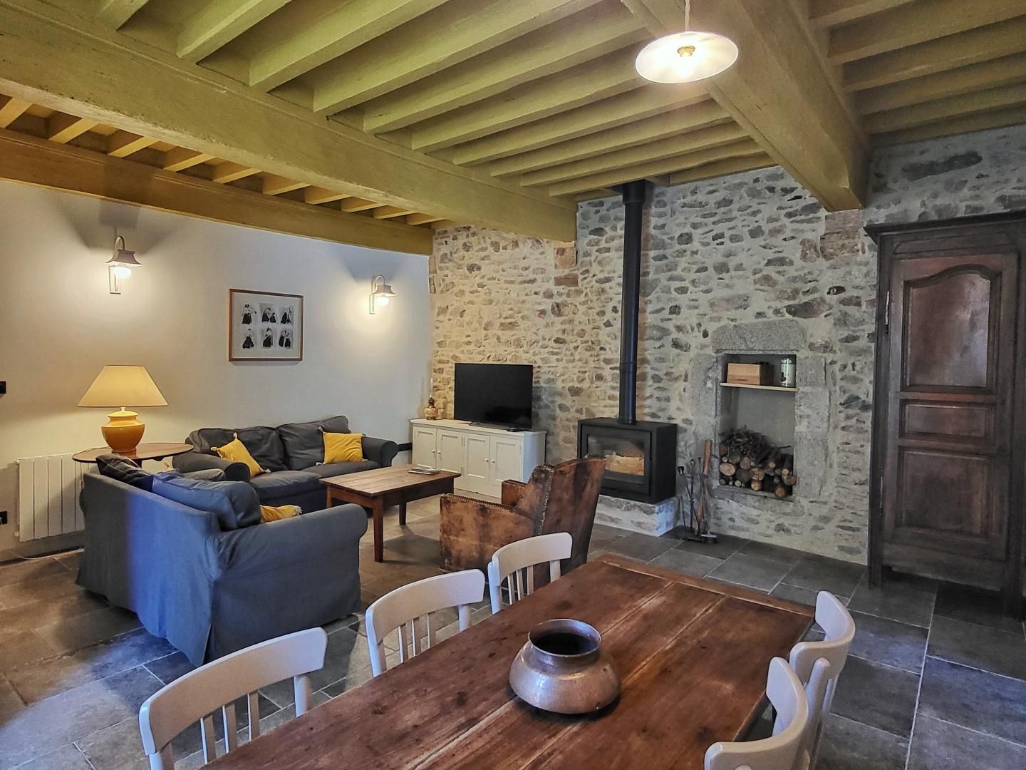 A cozy living room with a stone wall, a fireplace, a sofa, and a television.