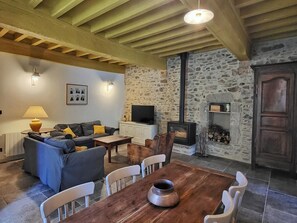 Ein gemütliches Wohnzimmer mit Steinwand, Kamin, Sofa und Fernseher.