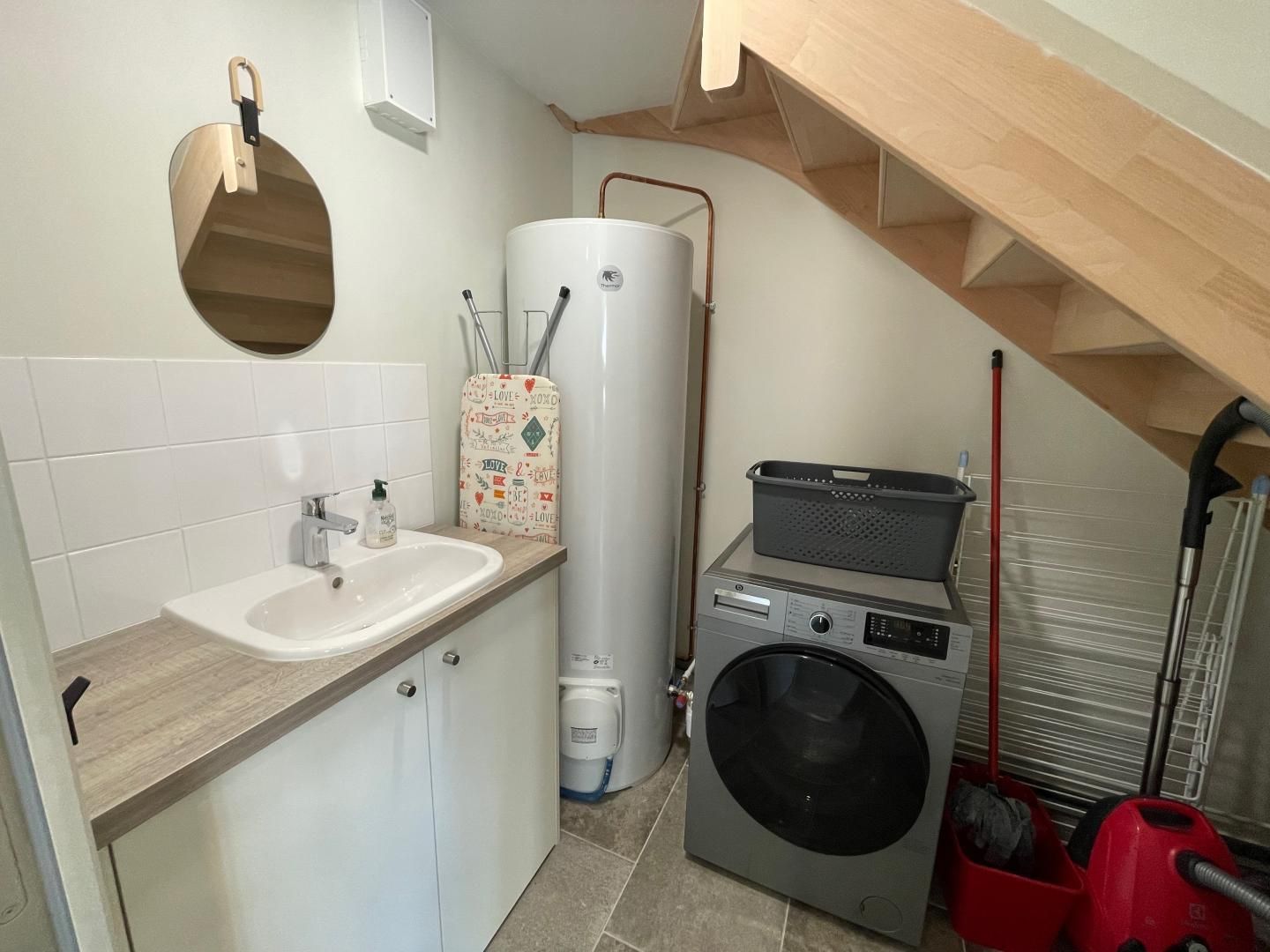 Una cocina compacta con un lavamanos, calentador de agua y lavadora.