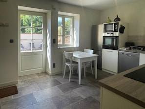 Una cocina moderna con una mesa y sillas blancas, horno empotrado, microondas y lavavajillas.