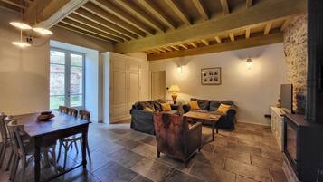 A spacious living area with a dining table, sofas, and a stone fireplace.