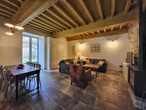 Un amplio espacio de sala con una mesa de comedor, sofás y una chimenea de piedra.