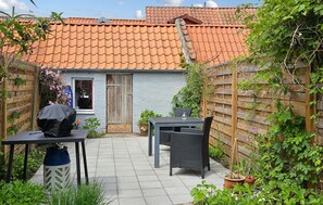 A patio area with a table and chairs, a barbecue grill, and potted plants. - 1 bedroom lovely home in Assens (Assens)