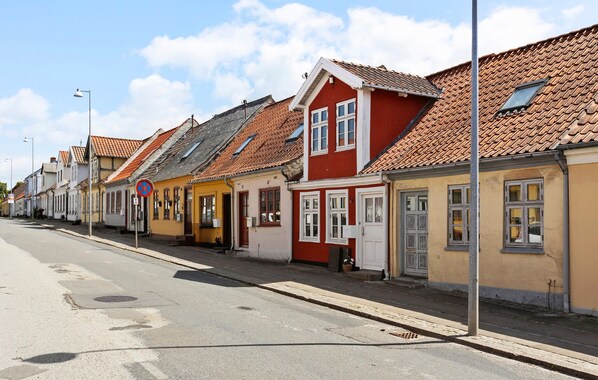 A row of traditional European-style buildings with red and yellow facades, a clear sky, and a no parking sign on the street. - 1 bedroom lovely home in Assens (Assens)