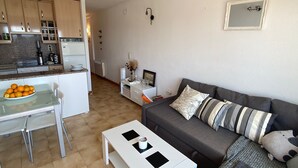 A compact living space with a kitchenette, a dining area, and a seating area with a sofa and a coffee table. - Well-equipped apt, in the center of town, near beach and shops, overlooking natural park and sea. (Empuriabrava)