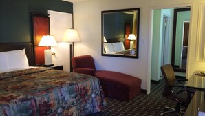 Une chambre d’hôtel avec un lit, un bureau, une chaise et un miroir.