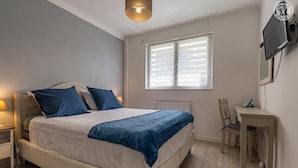 Ein Schlafzimmer mit einem Bett, Nachttischen, einem Schreibtisch und einem Stuhl.