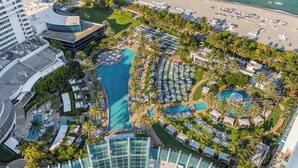 Vista aérea de un complejo turístico con múltiples piscinas, zonas de playa y abundante vegetación.
