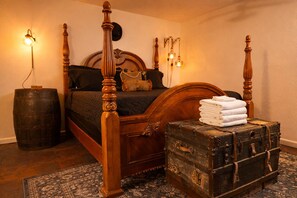 Ein Schlafzimmer mit einem Himmelbett, einem alten Koffer und einem Fass.