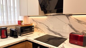 A kitchen with a Bosch microwave, toaster, and coffee maker on a marble countertop.