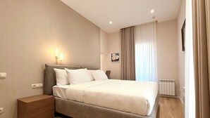 A neatly arranged bedroom with a bed, bedside tables, a wall-mounted light, and a radiator.