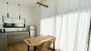 A modern kitchen with a dining table, chairs, and a hanging light fixture.