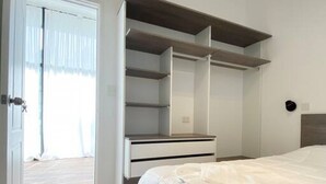A bedroom with a bed, a wardrobe, and a door leading to a balcony.