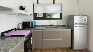 A compact kitchen with a built-in oven, microwave, and a stainless steel refrigerator.