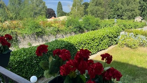 A garden with red flowers, green bushes, and a view of mountains and a lake. - Stresa Golf & Relax Romantik Suite (Gignese)