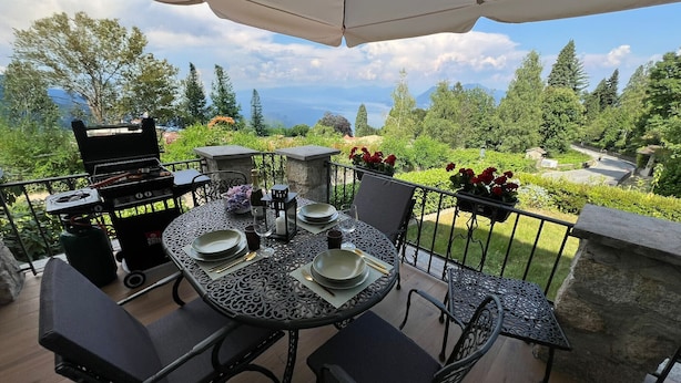 An outdoor patio with a table set for dining, a grill, and a scenic view of trees and mountains. - Stresa Golf & Relax Romantik Suite (Gignese)